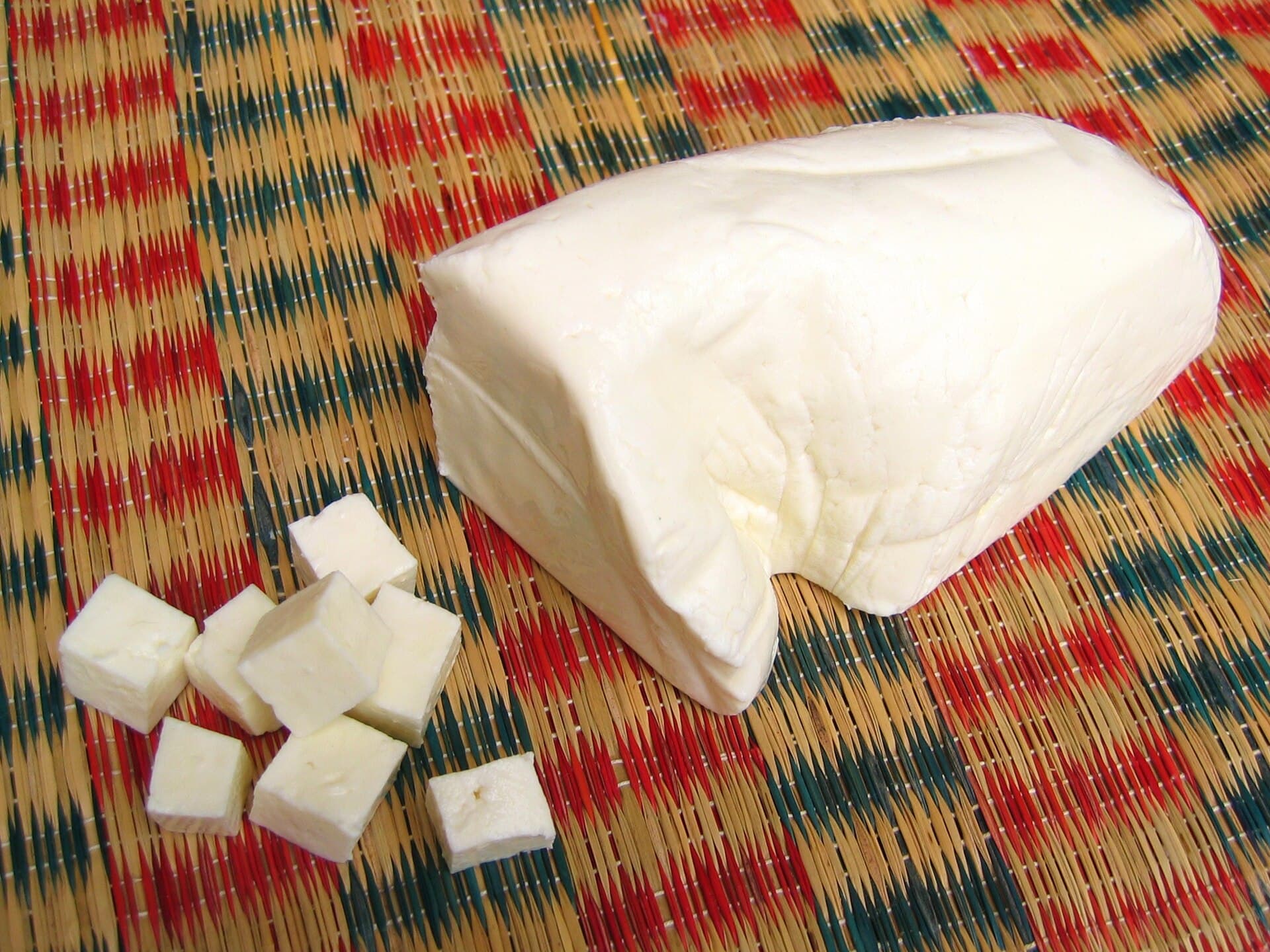 A pressed block of fresh paneer with cubes cut from it
